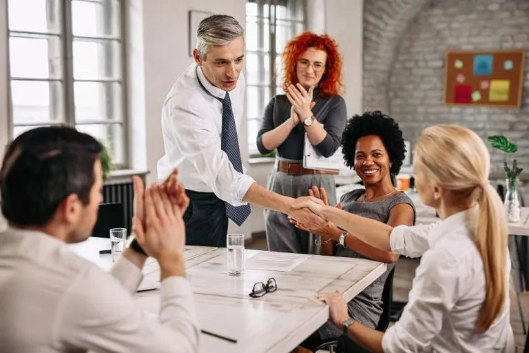 two-happy-business-people-shaking-hands-meeting-while-other-colleagues-are-applauding-them-office-fotor
